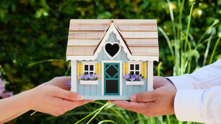 Two people holding a house in their hands.